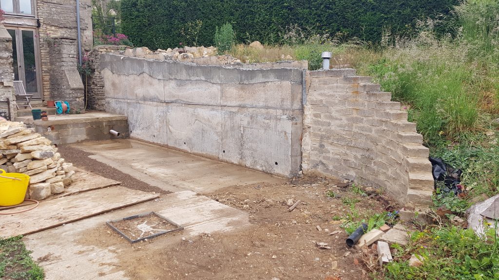 Dry stone facing on a concrete retaining wall in Oakridge Lynch, Stroud, Cotswolds.