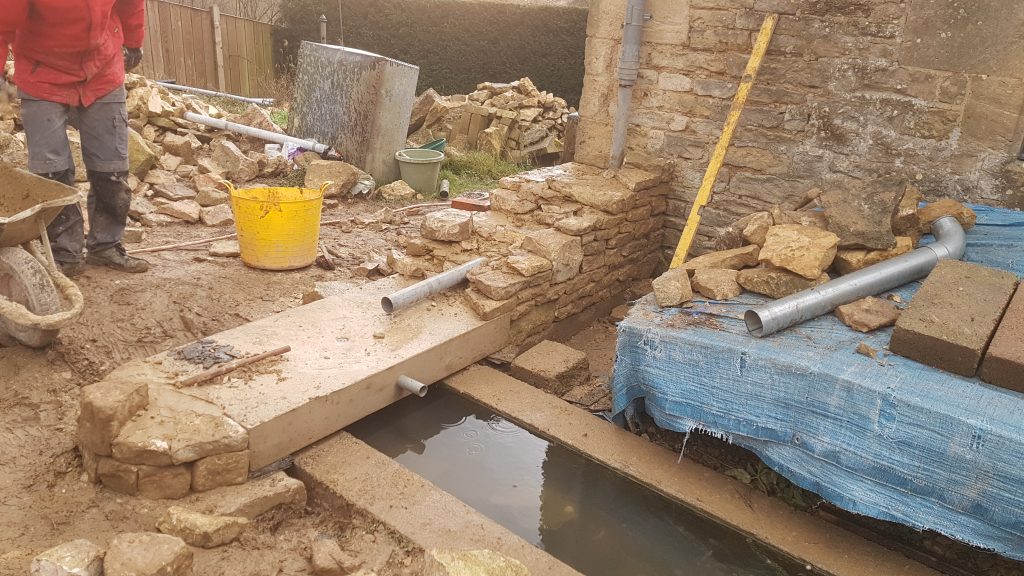 Building of a dry stone water feature and arch, going into a gatepost in Bisley, Stroud, Cotswolds