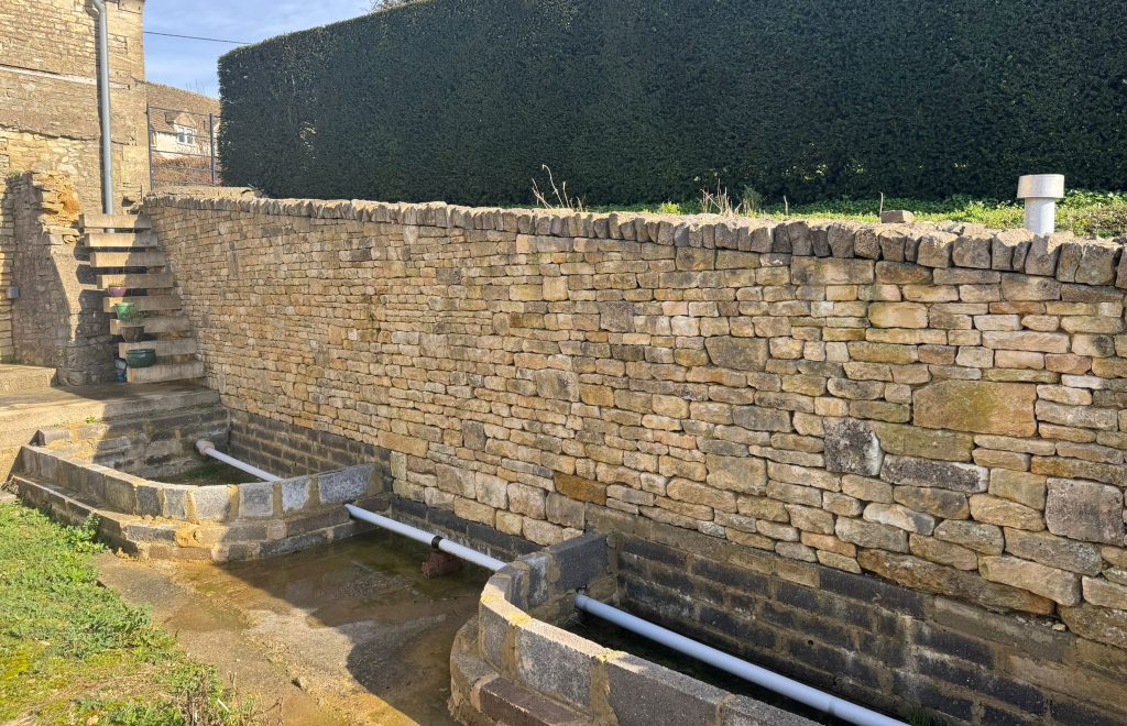 Dry stone effect facing on a concrete retaining garden wall in Oakridge Lynch, Stroud, Cotswolds