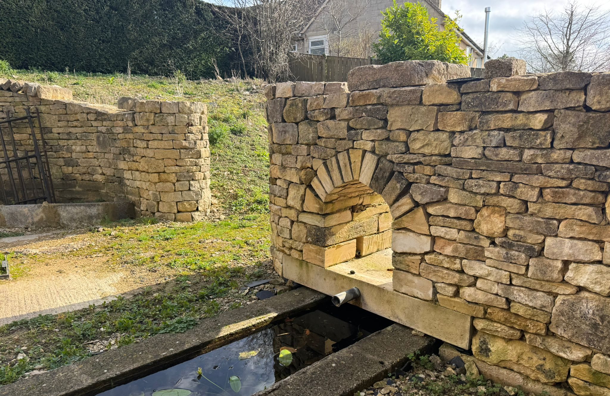 Building of a dry stone water feature and arch, going into a gatepost in Bisley, Stroud, Cotswolds