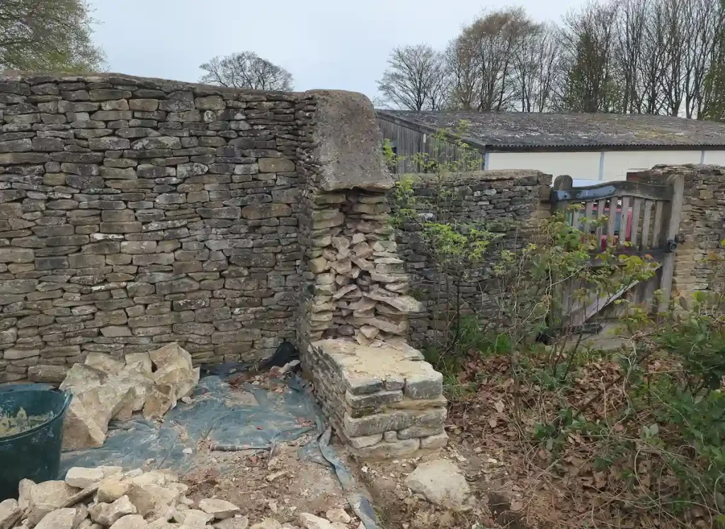 Traditional dry stone walling in progress with construction of a mortared wall head in Sherston near Tetbury.