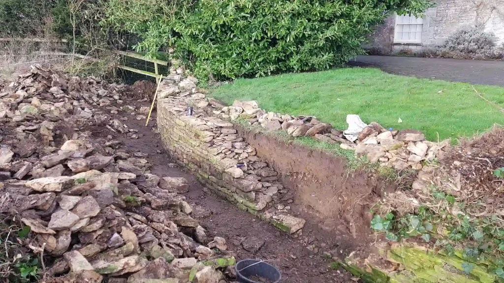 Dry stone wall restoration work beginning on damaged ha-ha in Kemble near Cirencester.