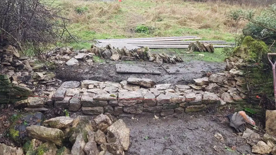 Rebuilding collapsed dry stone wall in Chalford, Stroud with initial courses being laid.